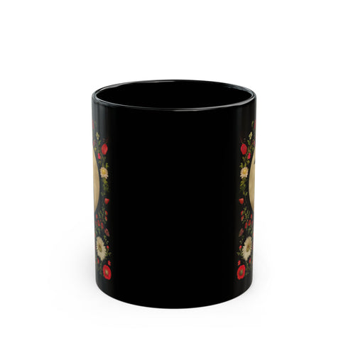 A black ceramic mug featuring a gothic design of a raven against a golden full moon, framed by a floral wreath of coral-colored daisies, white chrysanthemums, and delicate botanical elements. The design includes rich green foliage and small red buds arranged in a symmetrical pattern. The mug has a classic C-shaped handle with a glossy finish.